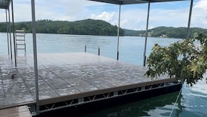 Un muelle techado que se extiende sobre el agua, con vista a una colina boscosa al fondo.