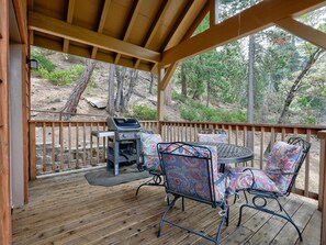 Une terrasse extérieure couverte, équipée d’un barbecue, de chaises en métal et d’une table.