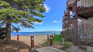 Une propriété située en bord de mer, offrant une vue dégagée sur l’océan, avec un chemin menant à la plage et un bâtiment doté de balcons.