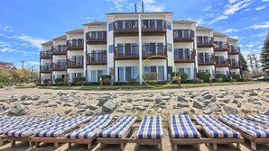 Un hôtel à plusieurs étages doté de balcons, situé en bord de plage, avec une plage de sable devant et des chaises longues.