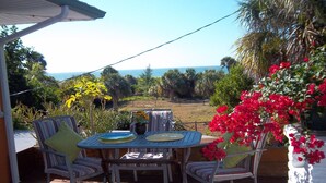 A patio with a table and chairs, overlooking a view of the sea and greenery. - Gulfside 1Br/1Ba Captain's Quarters On Anna Maria Island (Holmes Beach)