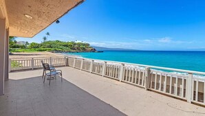 A balcony with a view of the ocean, a chair, and a railing.