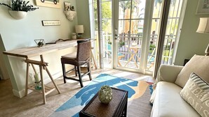 Un salon comprenant un canapé, une table basse, un fauteuil et une table à manger. Une grande fenêtre offre une vue sur l’extérieur.