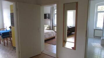 Ein Zimmer mit einem Bett, einem kleinen Tisch mit Stühlen, einem Spiegel und einem Fenster.
