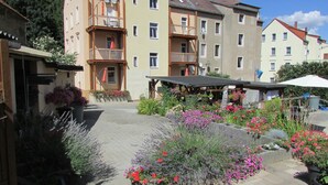 A courtyard with a paved walkway, potted plants, and a covered seating area. - NoOaks (Meissen)