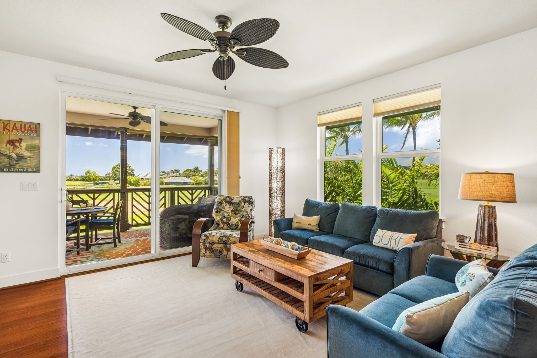 A spacious living room with a large sofa, a coffee table, and a ceiling fan.
