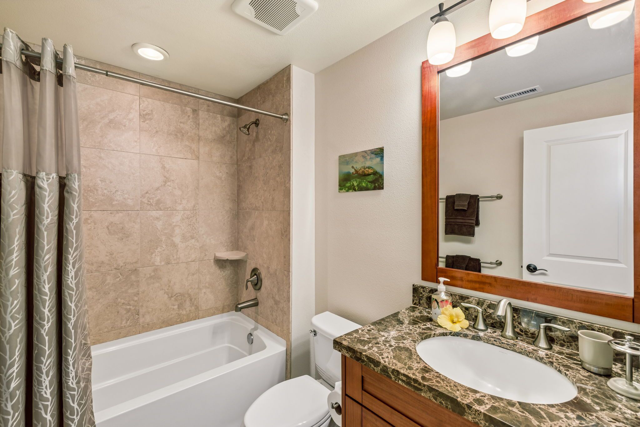Une salle de bain avec une baignoire, des toilettes, un lavabo et un miroir avec éclairage.
