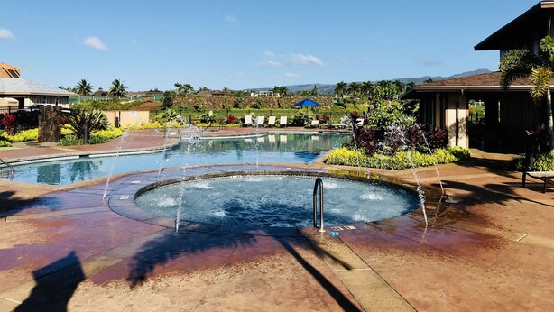 A pool area with multiple water features, including a central fountain and surrounding water jets. - Luxury condo with central A/C and golf and ocean views (Koloa)
