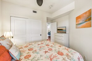A bedroom with a bed, a dresser, a television, and a painting on the wall. - Luxury condo with central A/C and golf and ocean views (Koloa)