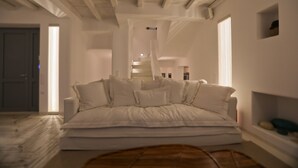 A spacious room with a large bed, a wooden floor, and a staircase leading to an upper level. - Villa Moonflower (Mykonos)
