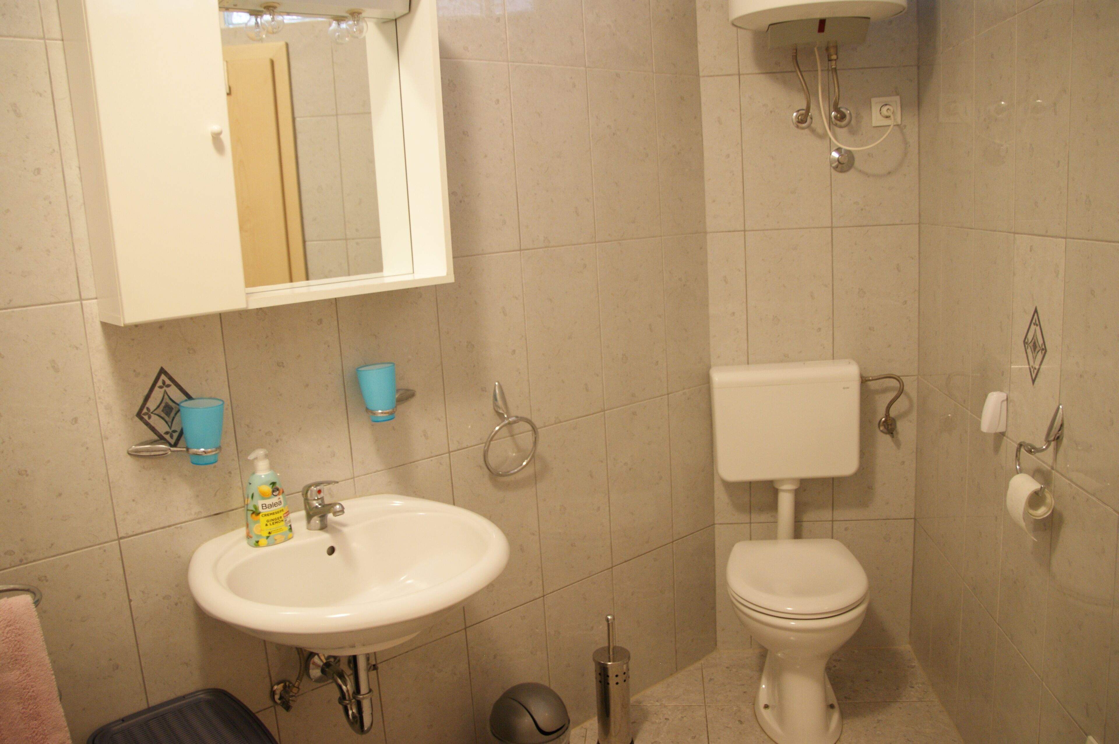 A bathroom with a sink, toilet, and mirror.