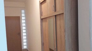 Ein Flur mit einem Holzschrank, einer Tür und einem Fenster mit Jalousien.