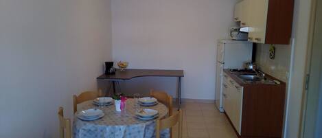 A compact kitchen with a dining table set for two, a small refrigerator, and a microwave.