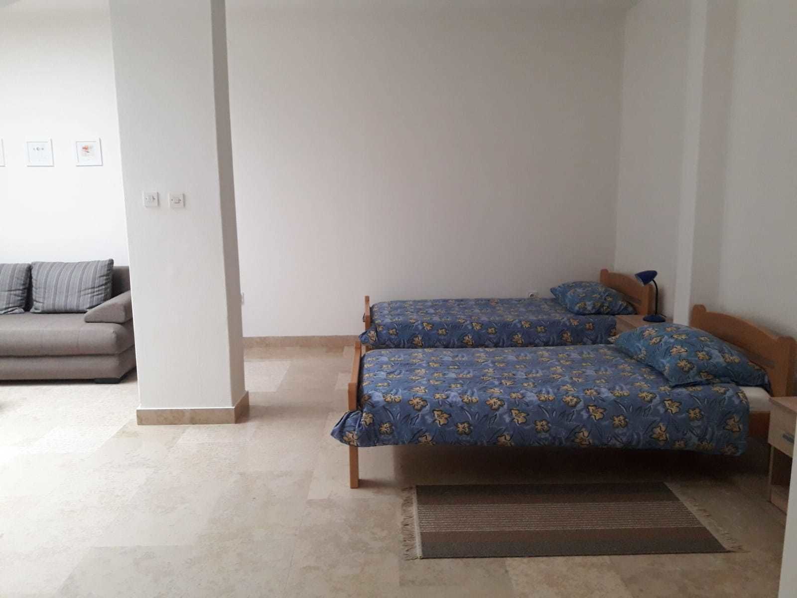 A room with two single beds, a sofa, and a small table.