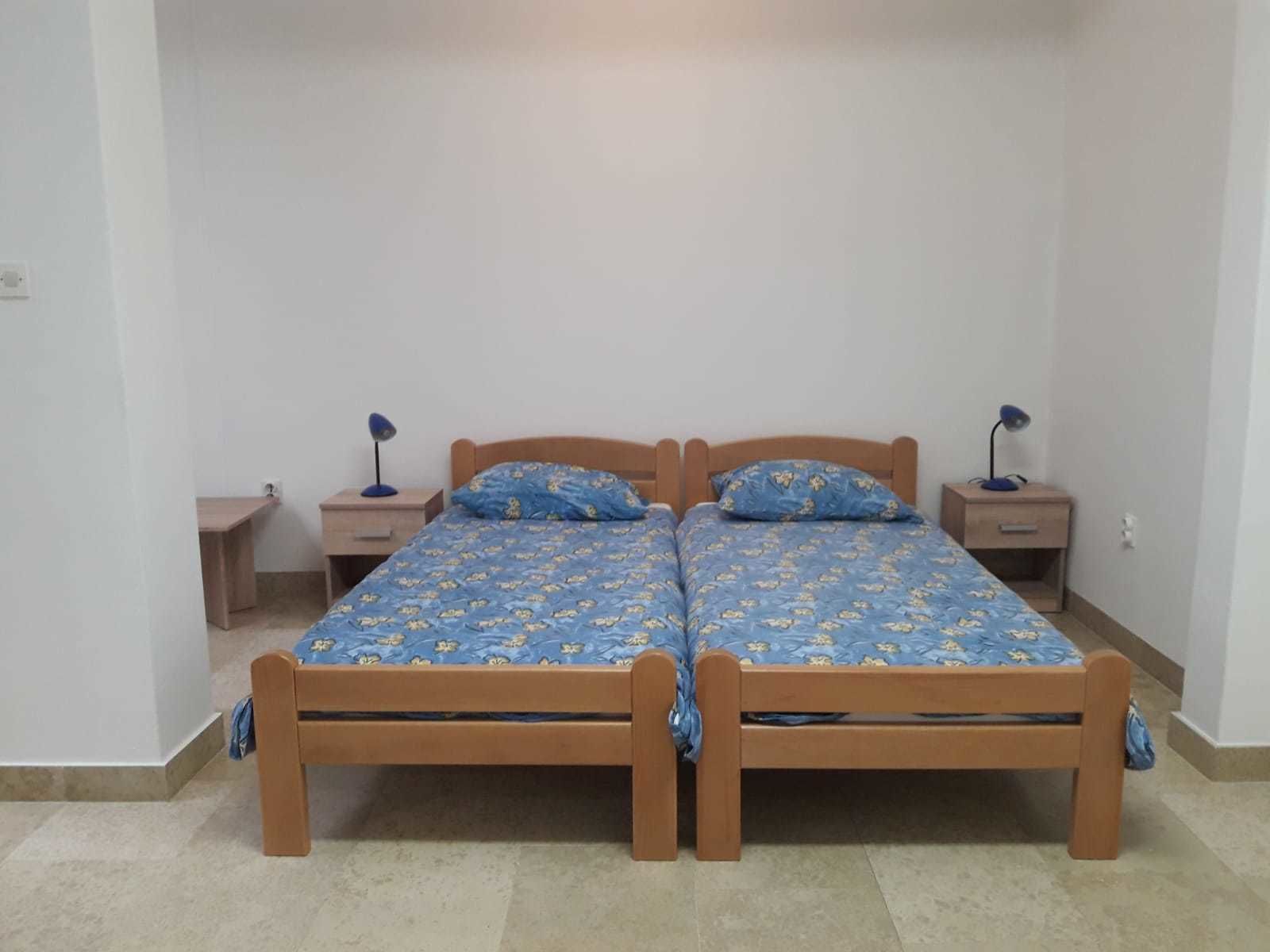 A double bed with a floral bedspread, two bedside tables with lamps, and a small wooden nightstand.