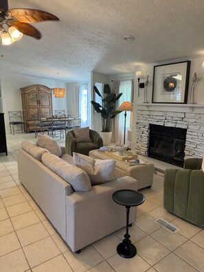 Relax in this stylish living room with a beige sectional sofa, green armchair, and a fireplace.