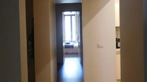 A narrow hallway with wooden flooring leading to a room with a bed and a window. - Papali (Catania)