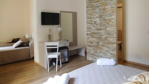 A bedroom with a bed, a desk, a chair, a TV, and a bathroom visible through an open door. - Papali (Catania)
