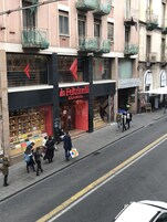 En gatubild med en bokhandel som heter ”La Feltrinelli” på bottenvåningen, och som har en stor utställning av böcker i skyltfönstret.