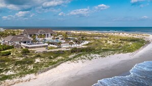 A beachfront property with a large house, a swimming pool, and a beach view.