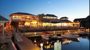 A waterfront restaurant with outdoor seating and boats docked nearby.