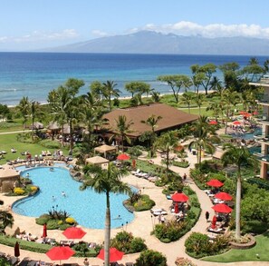 A resort with a large pool, palm trees, and a view of the ocean. - Ocean View Upgraded Top Fl HOKU711 Shaded Lanai see condo comparison chart  (Lahaina)