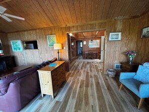 Ein Zimmer mit Holzboden, einer Couch, einem Tisch und einem Stuhl.