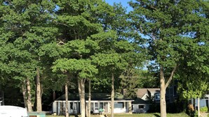 A lakeside property with a dock, a small shed, and a house with a covered porch. - Sandy Beach Cottage on Torch Lake, in Alden (Alden)
