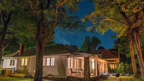 A house with a porch, a covered outdoor seating area, and a stone pillar. - Sandy Beach Cottage on Torch Lake, in Alden (Alden)