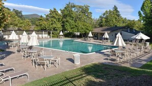 A pool area with lounge chairs, umbrellas, and a building in the background. - Getaway Suite at Silverado in Napa (Napa)