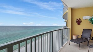 A balcony with a view of the ocean, a chair, and a wall decoration. - Emerald Isle 1303 - Front row beach chair service included! Affordable rates! (Panama City Beach)