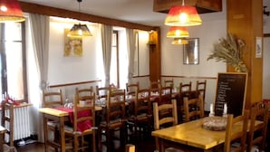 Un restaurant avec des tables et des chaises en bois, un menu écrit à la craie et des lampes suspendues.