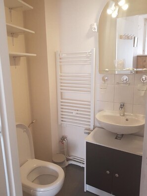A bathroom with a toilet, a sink, a mirror, and a towel rack.