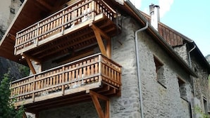 Un bâtiment en pierre doté d’un balcon en bois et d’une porte.