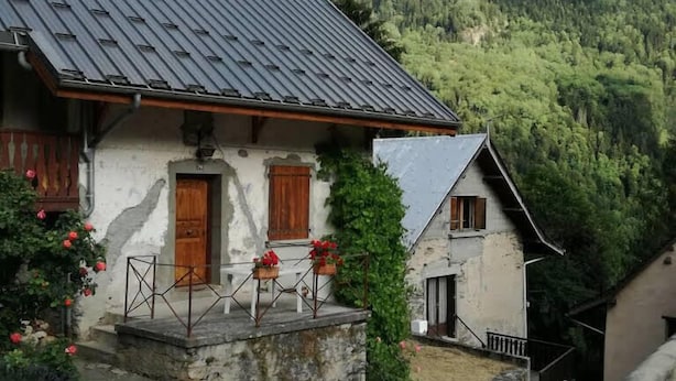 Un chalet traditionnel doté d’un toit à pente, de volets en bois et de fondations en pierre.