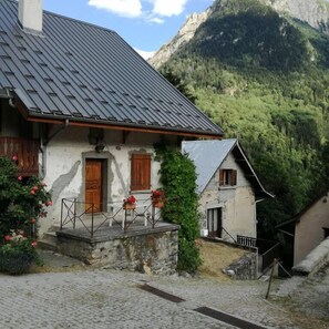 Ein traditionelles Chalet mit geneigtem Dach, Holzläden und einem Steinfundament.