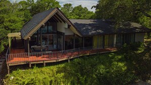 Une maison avec une grande façade vitrée, une véranda et un toit rouge.