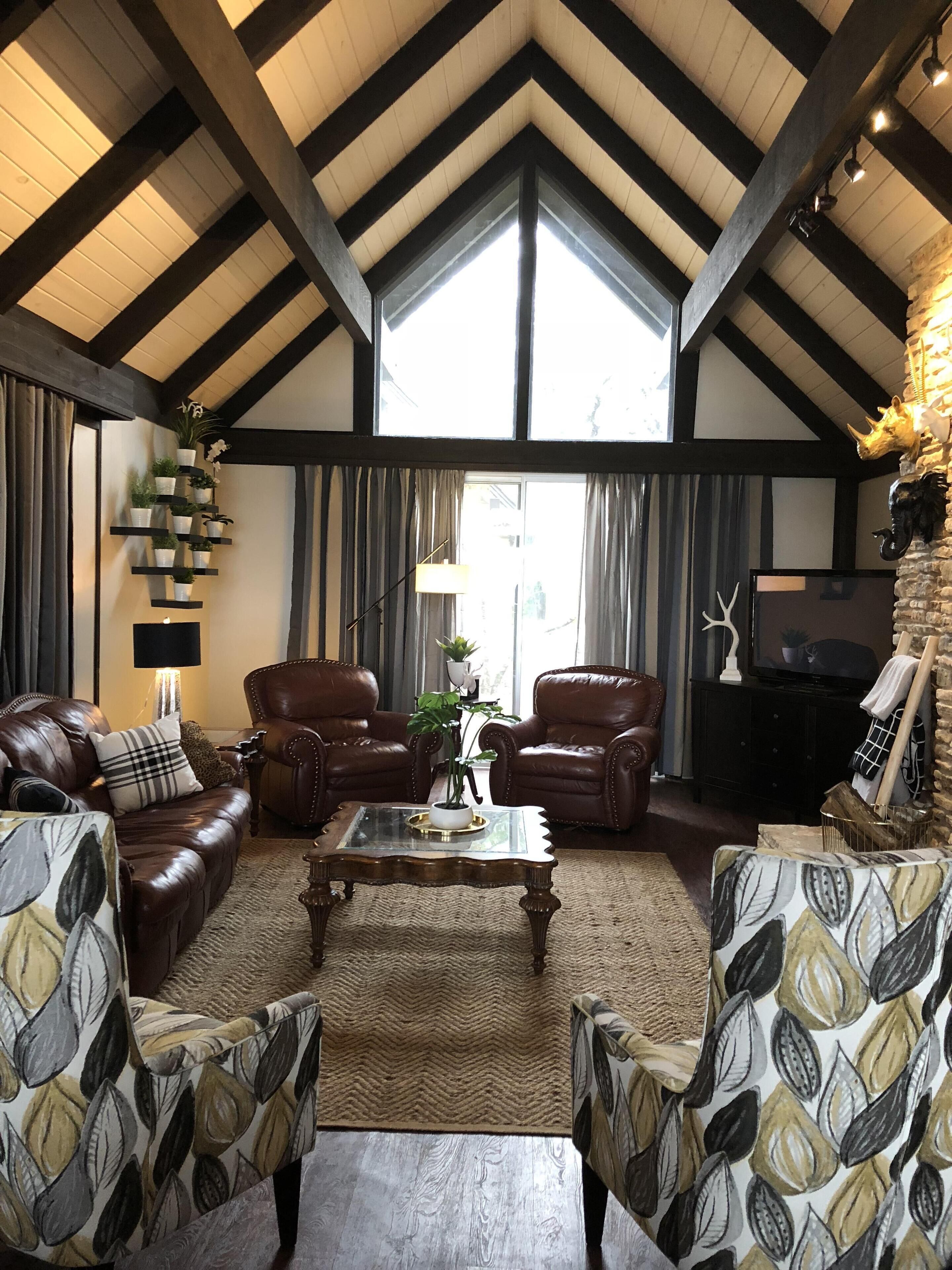A spacious living room with leather sofas, a coffee table, and a fireplace.
