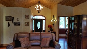 Uma sala de estar espaçosa com um sofá de couro, um lustre e teto de madeira.