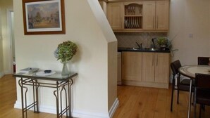 A kitchen with wooden cabinets, a dining table with chairs, and a vase with flowers on a small table.