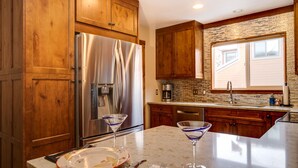 A kitchen with wooden cabinets, stainless steel appliances, a marble countertop, and a window with blinds. - Spacious Mountain Townhouse. Great Location! (Breckenridge)