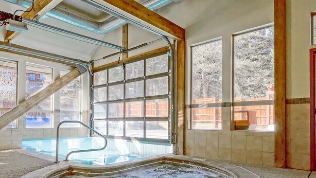 An indoor swimming pool with a hot tub, large windows, and a view of the outside. - Spacious Mountain Townhouse. Great Location! (Breckenridge)