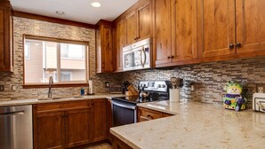 A kitchen with wooden cabinets, a stainless steel dishwasher, a microwave, and a stove. - Spacious Mountain Townhouse. Great Location! (Breckenridge)
