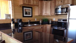 Una cocina con armarios de madera, un refrigerador de acero inoxidable, un microondas y una encimera de granito.