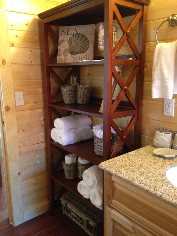 A wooden shelf with towels, baskets, and a sign reading "SEA Shell". - Homer Beachside cabins (Homer)