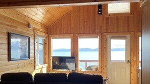 Una habitación de cabaña acogedora con paredes de madera, un ventanal grande, un televisor y una cama.