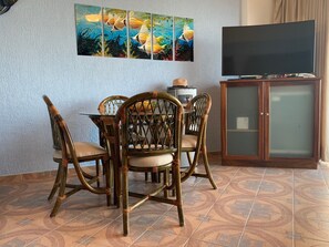 Ein Essbereich mit Tisch, Stühlen, einem Fernseher und einem Schrank.
