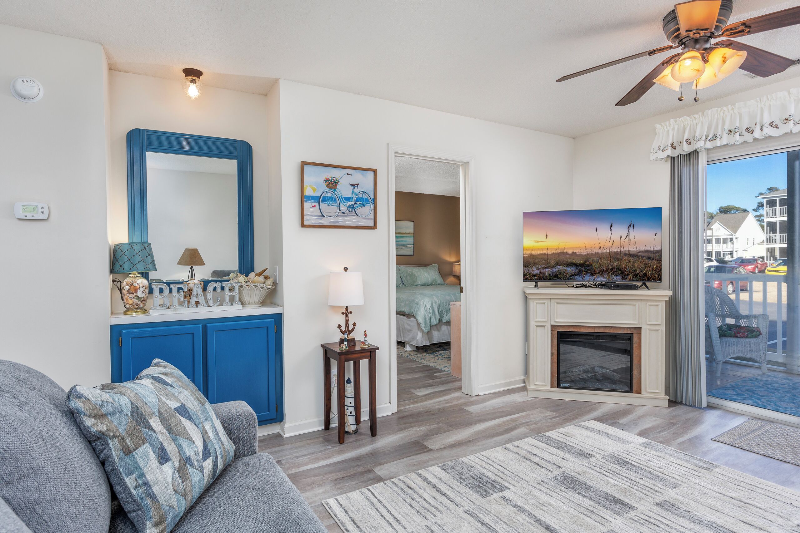 A living room with a blue cabinet, a fireplace, and a large window with a view of the outside.