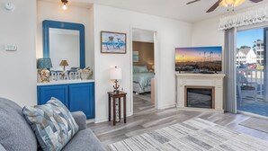 A living room with a blue cabinet, a fireplace, and a large window with a view of the outside. - Affordable cozy 2 bedroom condo 1st floor screened in patio in gated community. (North Myrtle Beach)