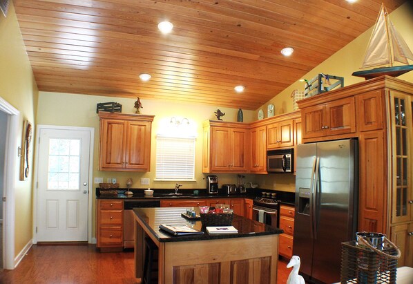 Enjoy cooking in this kitchen with a central island, wooden cabinetry, and stainless steel refrigerator.